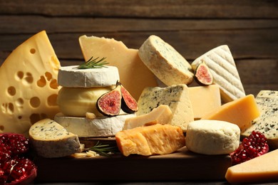 Photo of Different types of cheese, rosemary, figs and pomegranate on table