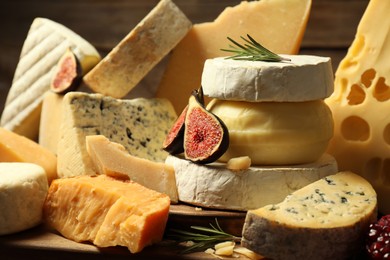 Photo of Different types of cheese, rosemary and fig on table, closeup