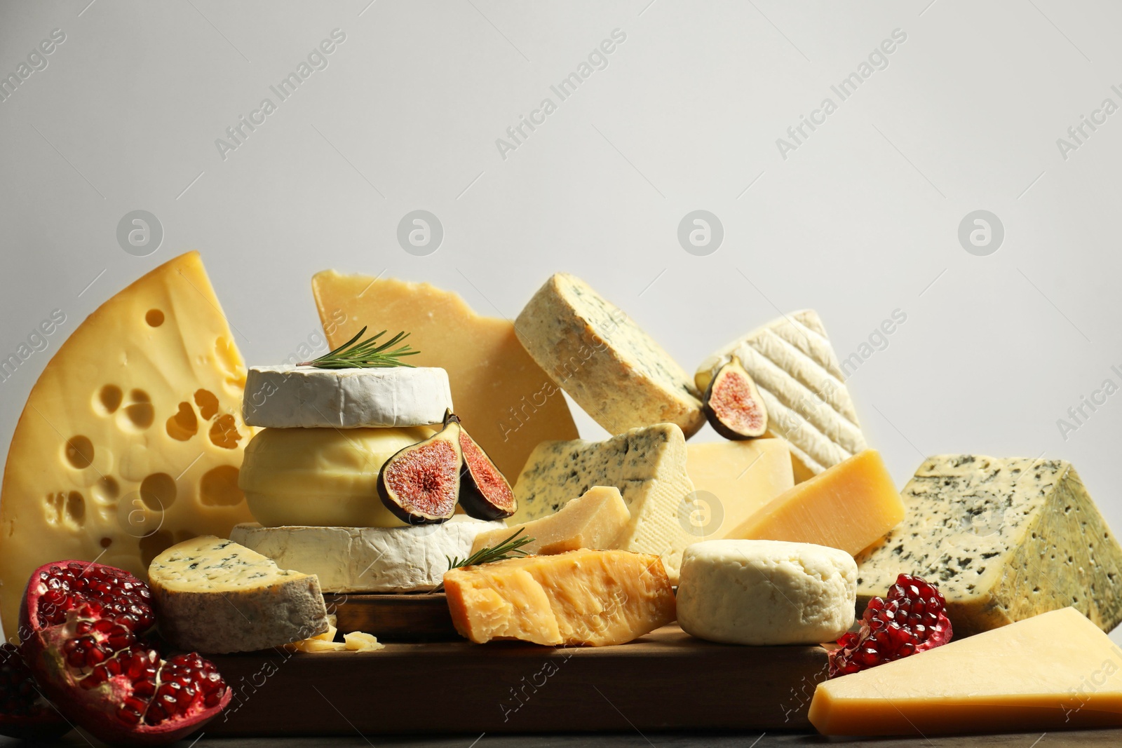 Photo of Different types of cheese, rosemary, figs and pomegranate on table