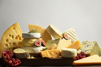 Photo of Different types of cheese, rosemary, figs and pomegranate on table