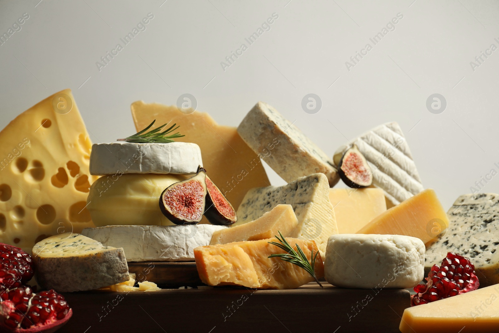 Photo of Different types of cheese, rosemary, figs and pomegranate on table