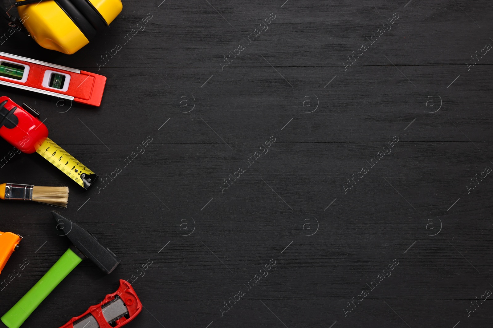 Photo of Different construction materials and tools on black wooden table, flat lay. Space for text