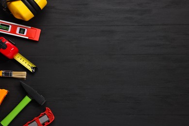 Photo of Different construction materials and tools on black wooden table, flat lay. Space for text