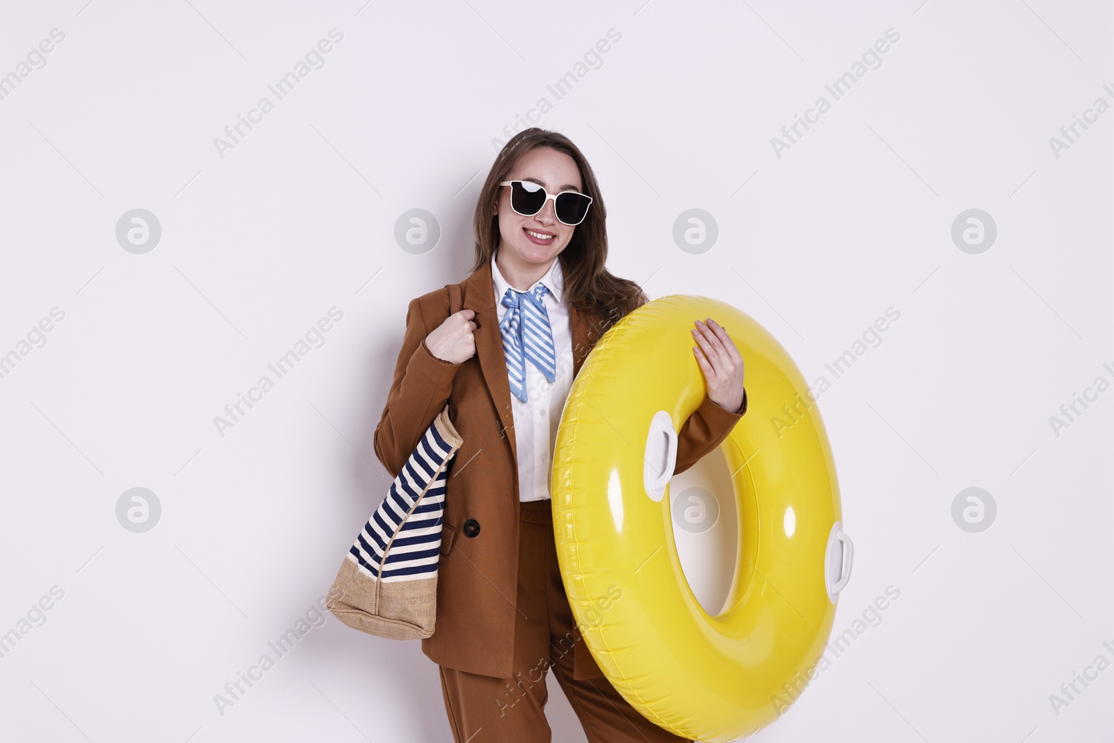 Photo of Businesswoman with inflatable ring, bag and sunglasses on white background