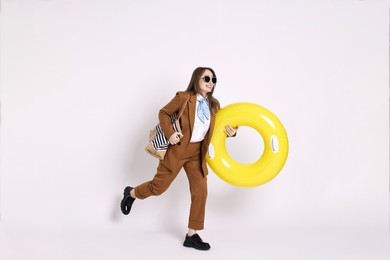 Photo of Businesswoman with inflatable ring, bag and sunglasses on white background