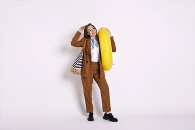 Photo of Businesswoman with inflatable ring, bag and sunglasses on white background