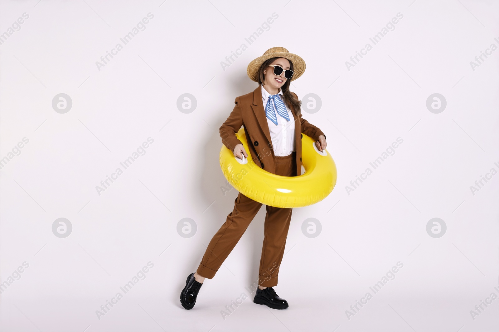 Photo of Businesswoman with inflatable ring, straw hat and sunglasses on white background