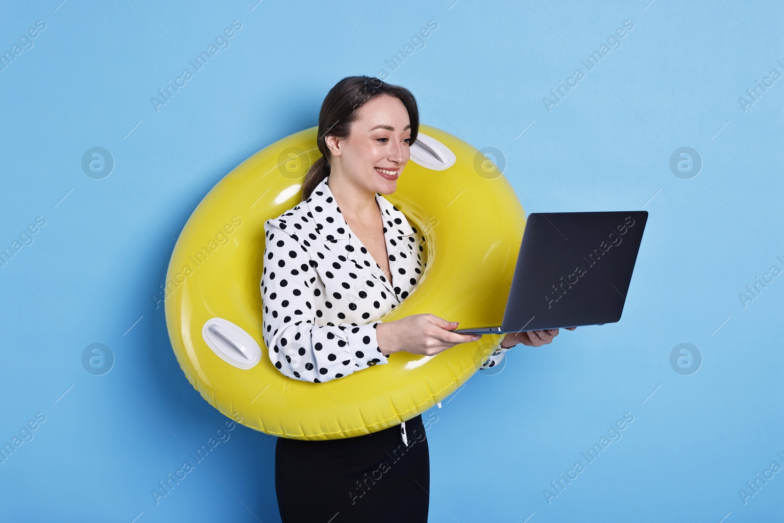 Photo of Businesswoman with inflatable ring and laptop on light blue background