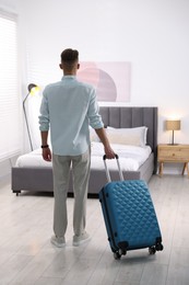 Photo of Man with suitcase in hotel room, back view