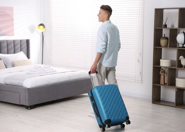 Photo of Man with suitcase in his hotel room