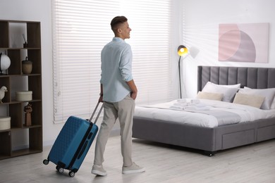 Photo of Man with suitcase in his hotel room