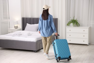 Photo of Woman with suitcase in hotel room, back view