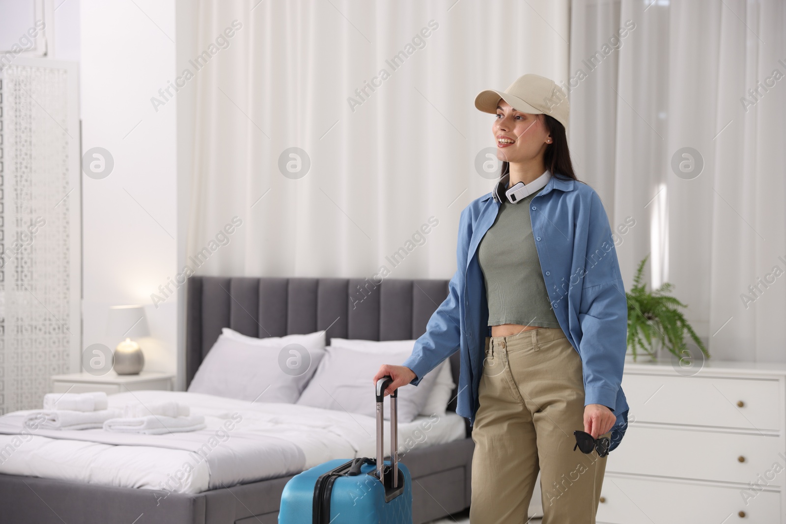 Photo of Woman with suitcase in her hotel room. Space for text