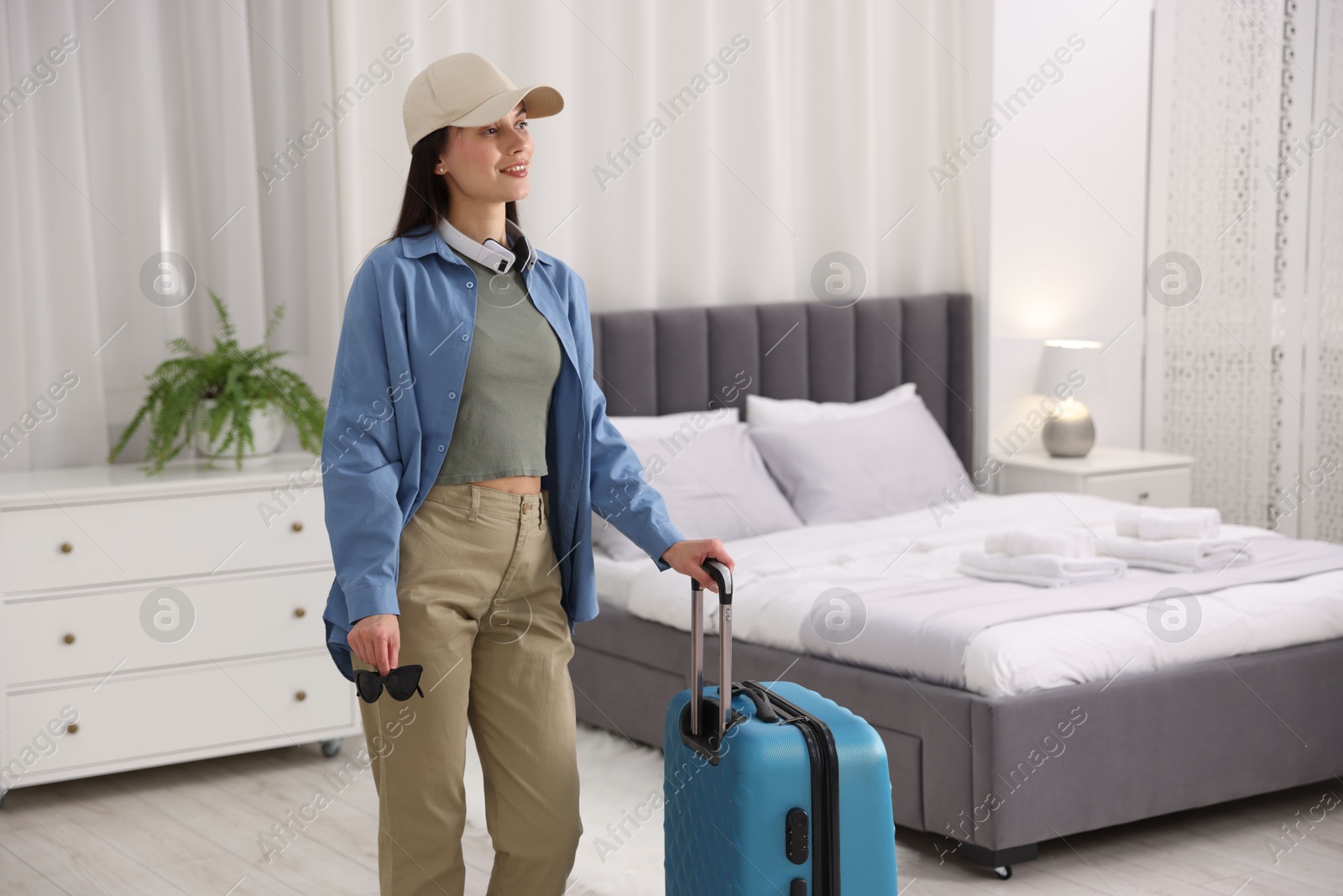 Photo of Woman with suitcase in her hotel room. Space for text