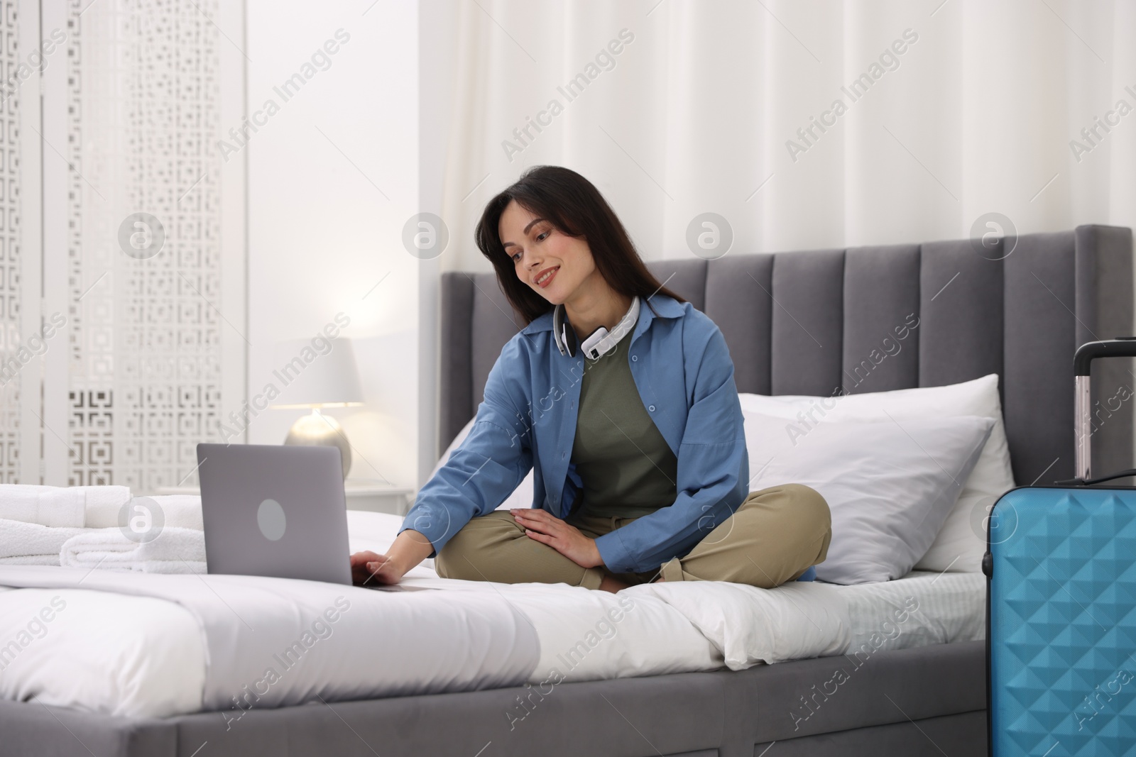 Photo of Woman with laptop on bed in her hotel room