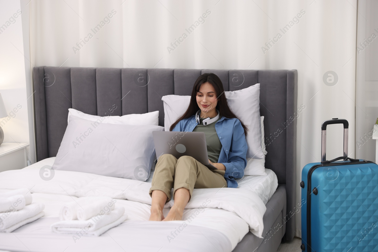 Photo of Woman with laptop on bed in her hotel room