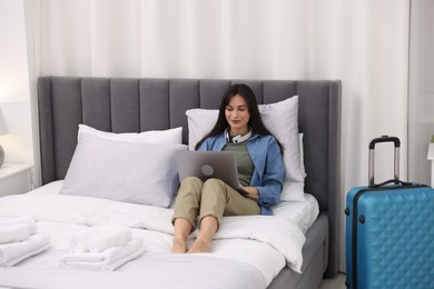 Photo of Woman with laptop on bed in her hotel room