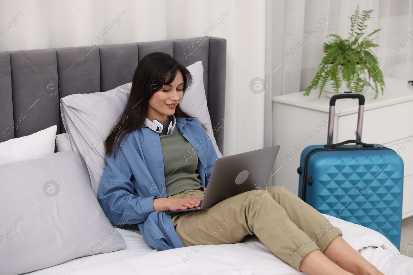 Photo of Woman with laptop on bed in her hotel room