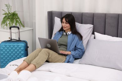 Photo of Woman with laptop on bed in her hotel room