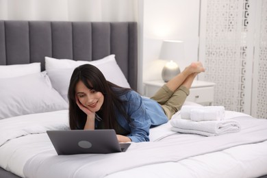 Photo of Woman with laptop on bed in her hotel room