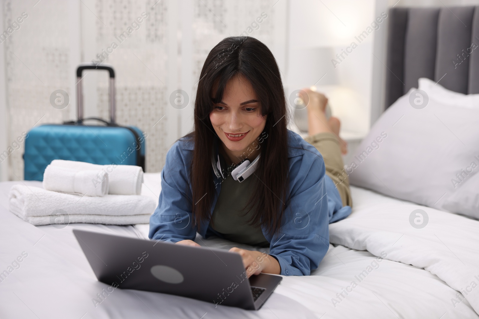 Photo of Woman with laptop on bed in her hotel room