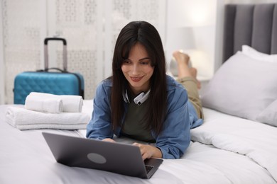 Photo of Woman with laptop on bed in her hotel room