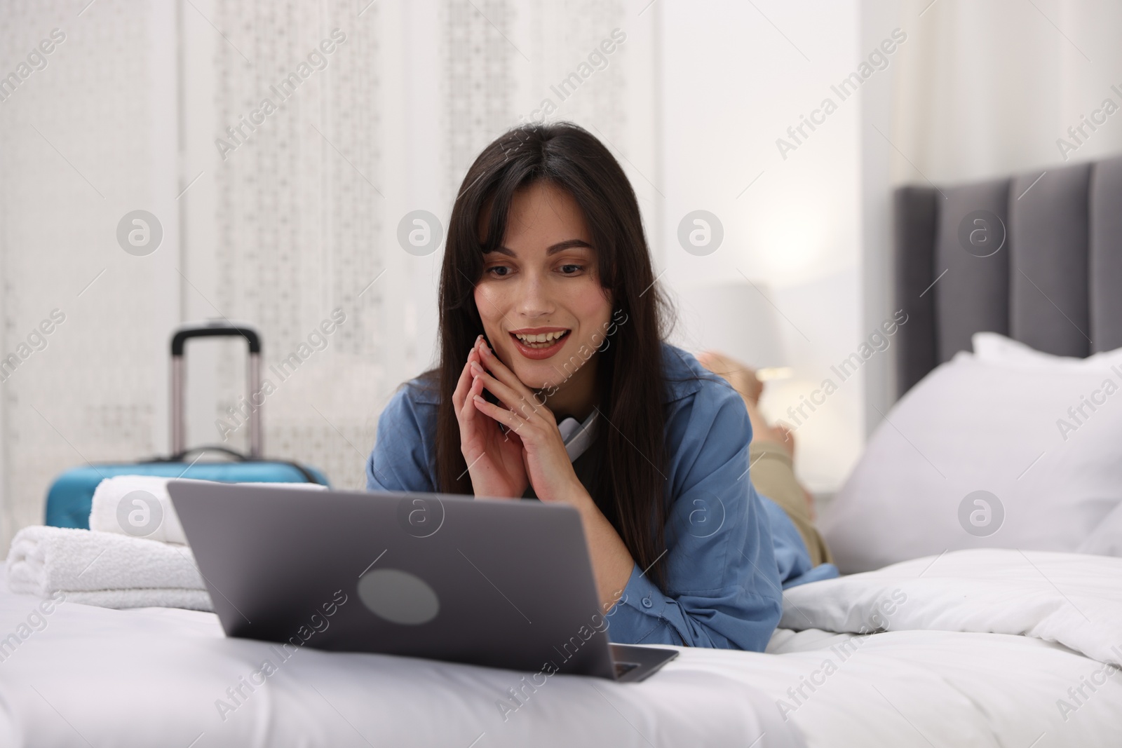 Photo of Woman with laptop on bed in her hotel room