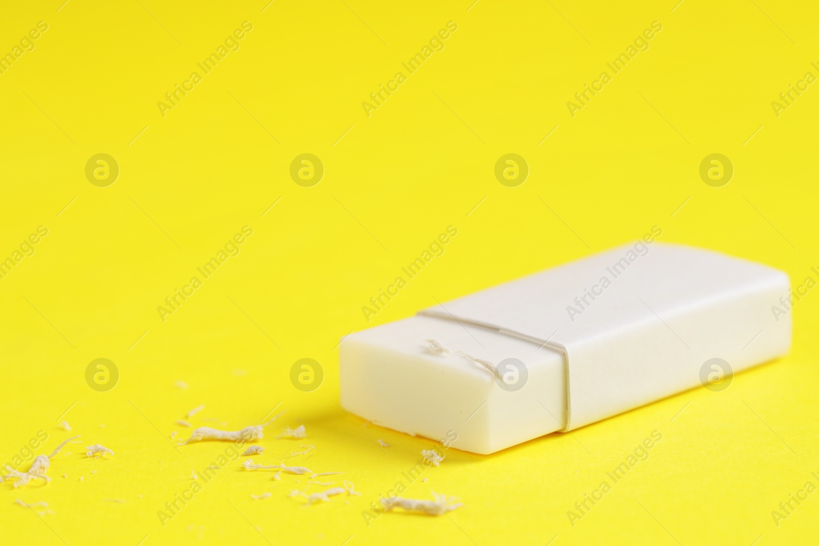 Photo of One eraser and scraps on yellow background, closeup. Space for text