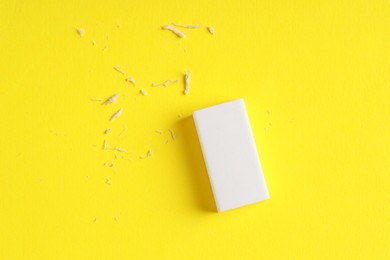 Photo of One eraser and scraps on yellow background, top view