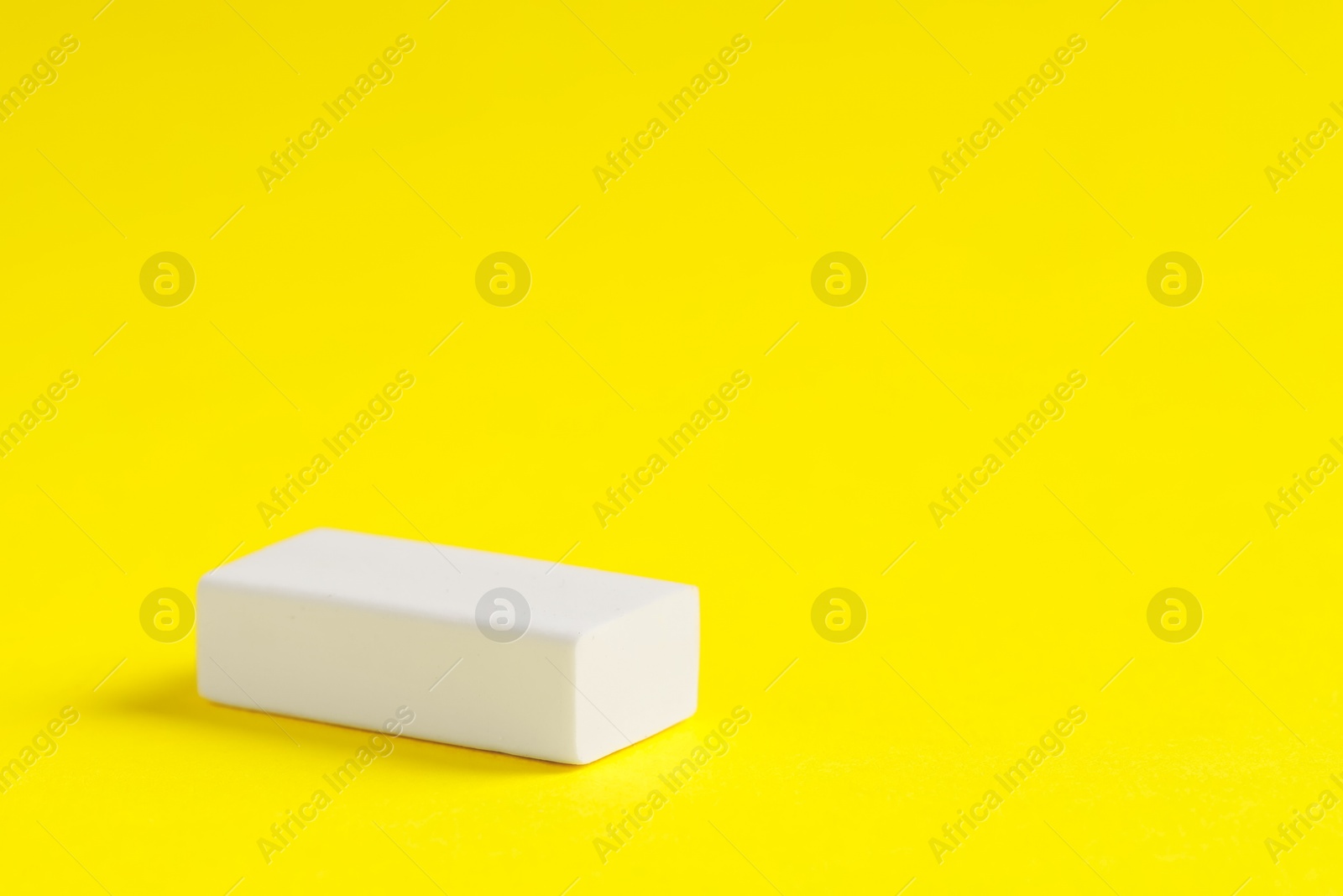 Photo of One eraser on yellow background, closeup. Space for text