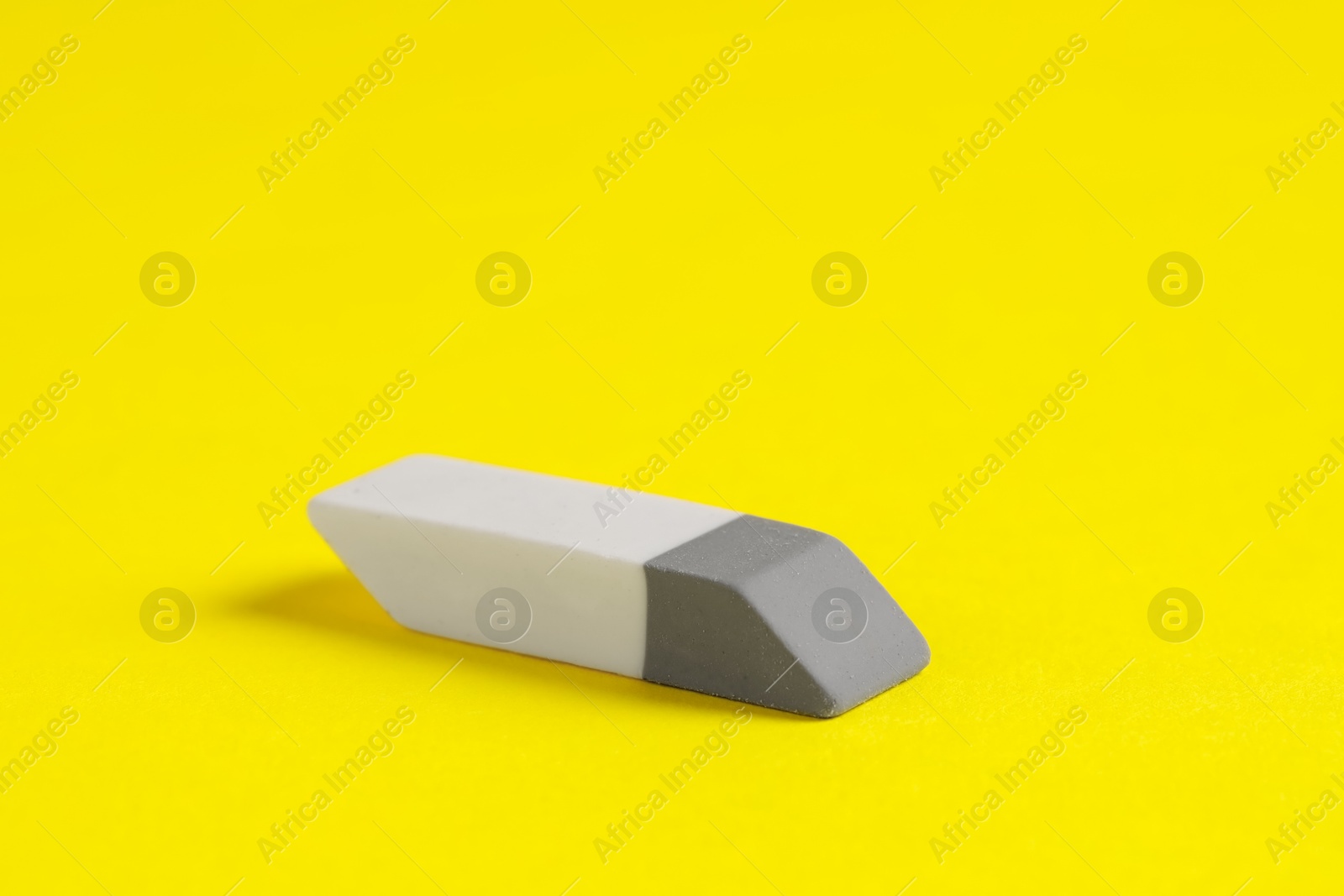 Photo of One eraser on yellow background, closeup view