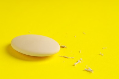 Photo of One eraser and scraps on yellow background, closeup. Space for text