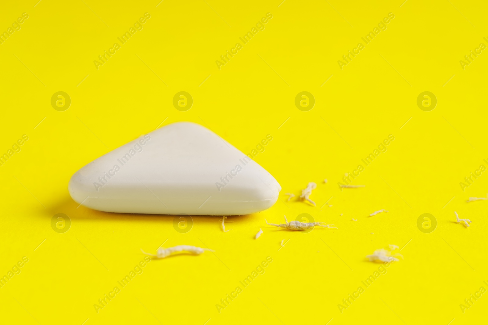 Photo of One eraser and scraps on yellow background, closeup