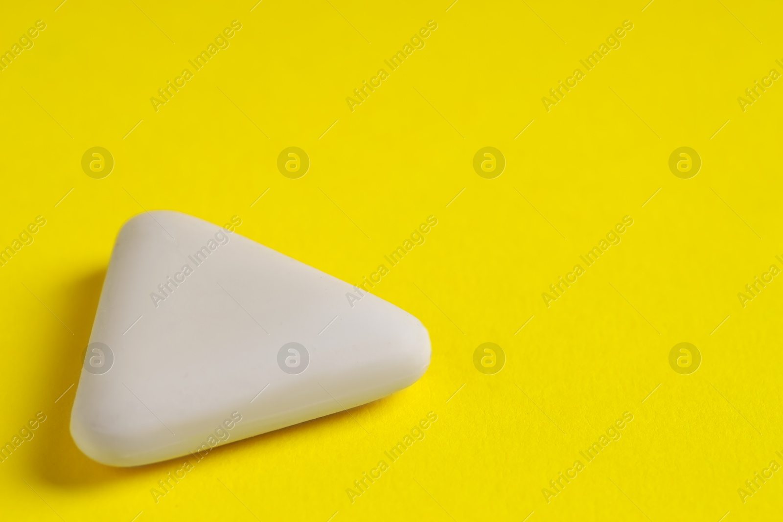 Photo of One eraser on yellow background, closeup. Space for text