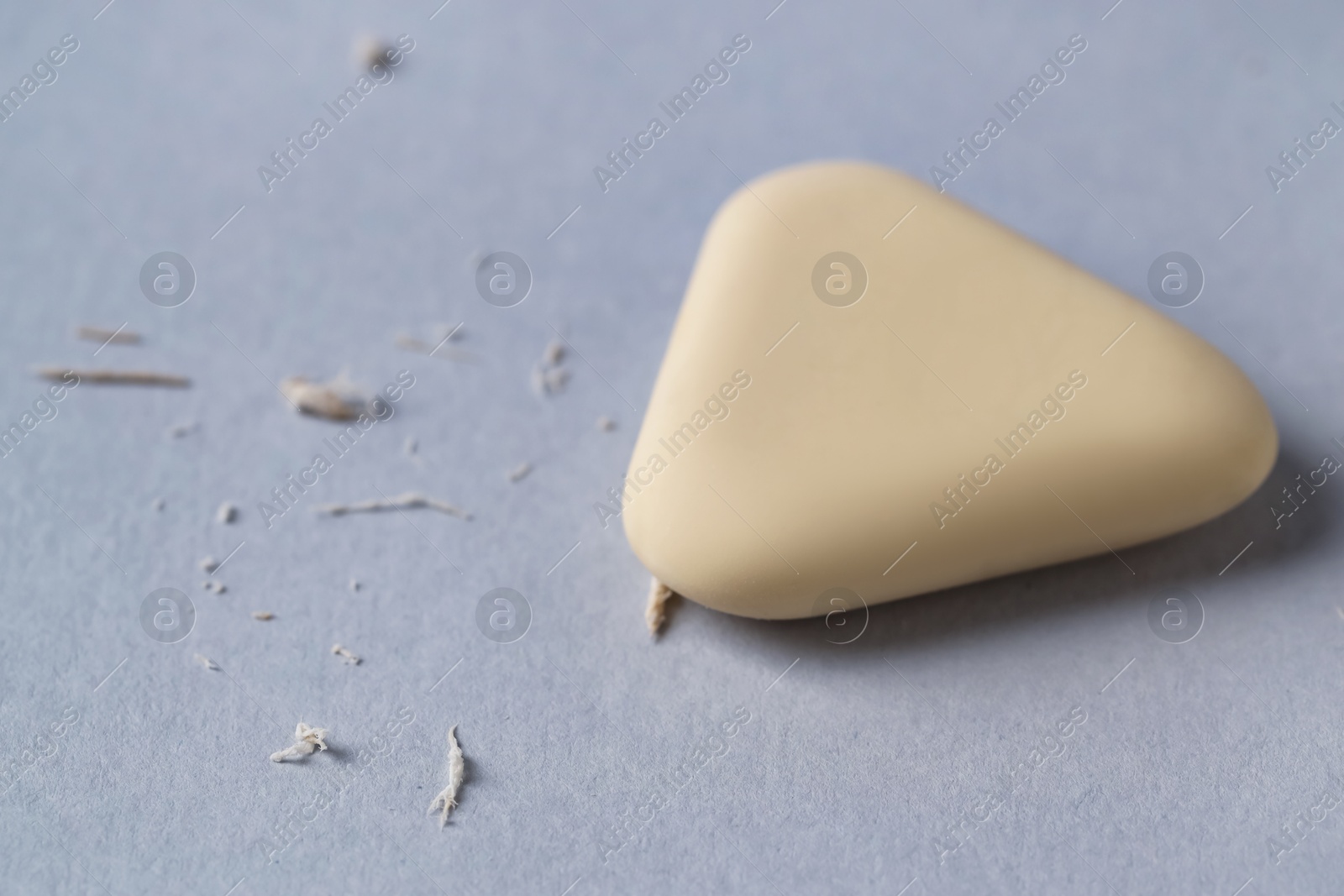 Photo of One eraser and scraps on grey background, closeup