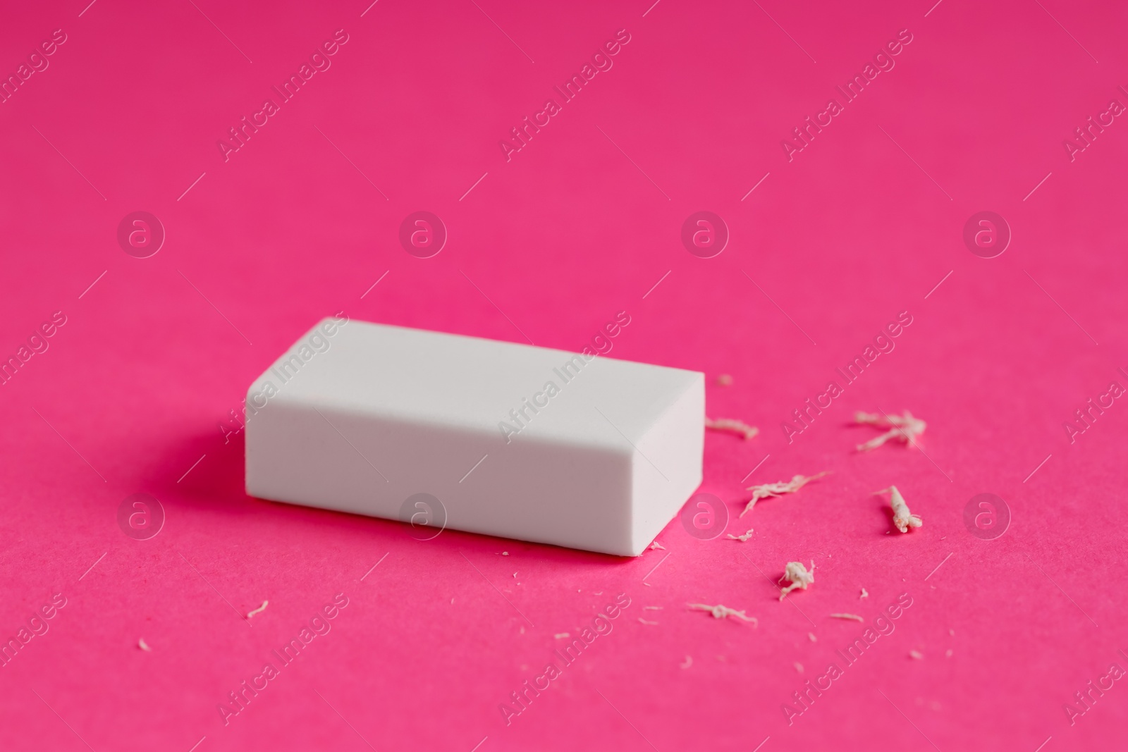 Photo of One eraser and scraps on pink background, closeup