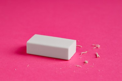 Photo of One eraser and scraps on pink background, closeup