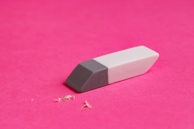 Photo of One eraser and scraps on pink background, closeup