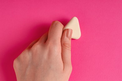 Photo of Woman using eraser on pink background, closeup