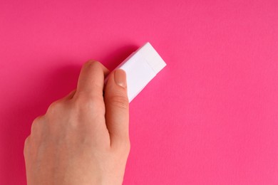 Photo of Woman using eraser on pink background, closeup. Space for text