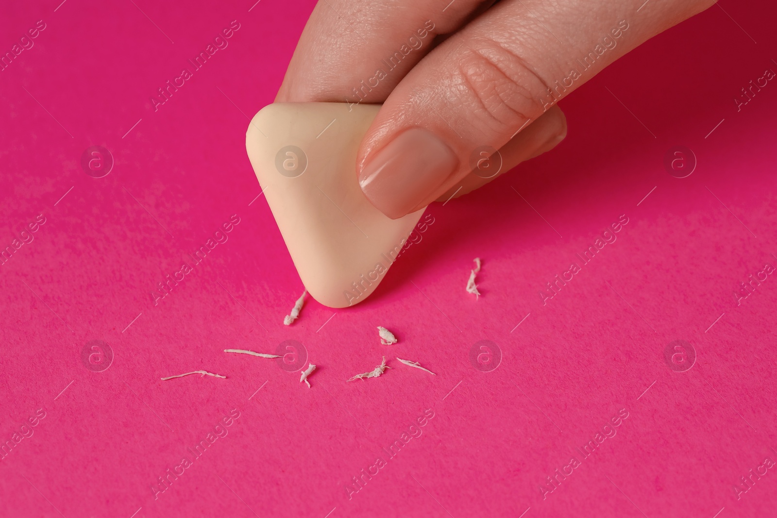 Photo of Woman using eraser on pink background, closeup