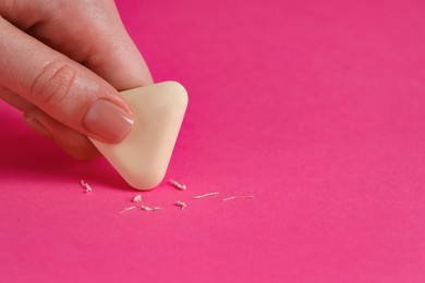 Photo of Woman using eraser on pink background, closeup. Space for text