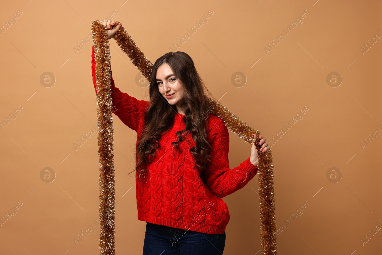 Photo of Happy young woman with tinsel on beige background