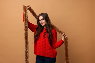 Photo of Happy young woman with tinsel on beige background