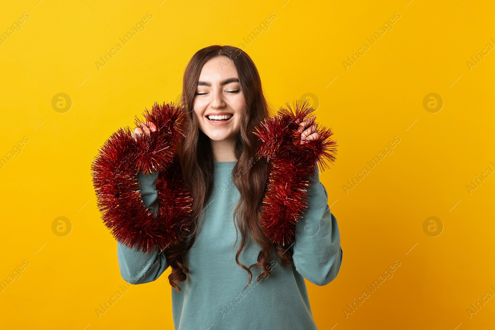 Photo of Happy young woman with tinsel on orange background