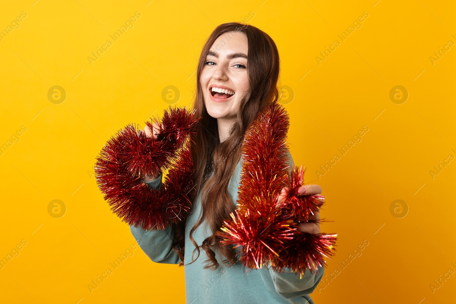 Photo of Happy young woman with tinsel on orange background