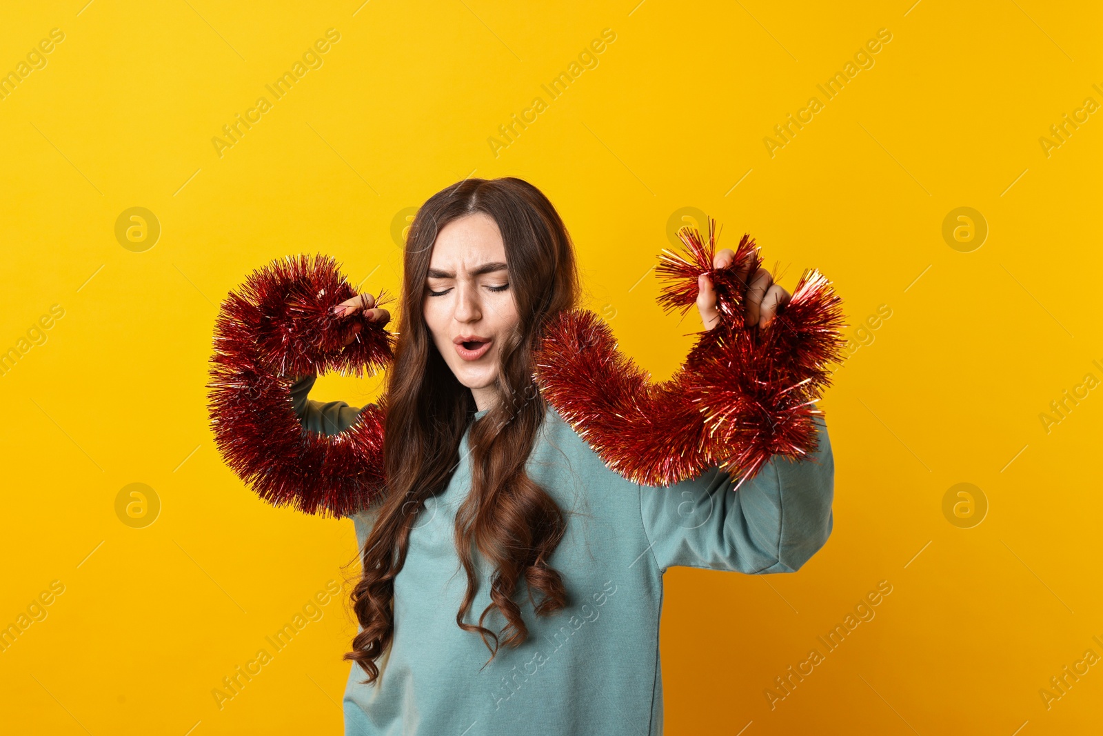 Photo of Emotional young woman with tinsel on orange background