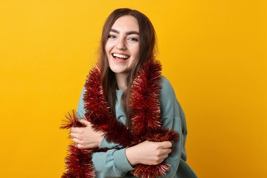 Photo of Happy young woman with tinsel on orange background