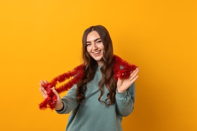 Photo of Happy young woman with tinsel on orange background