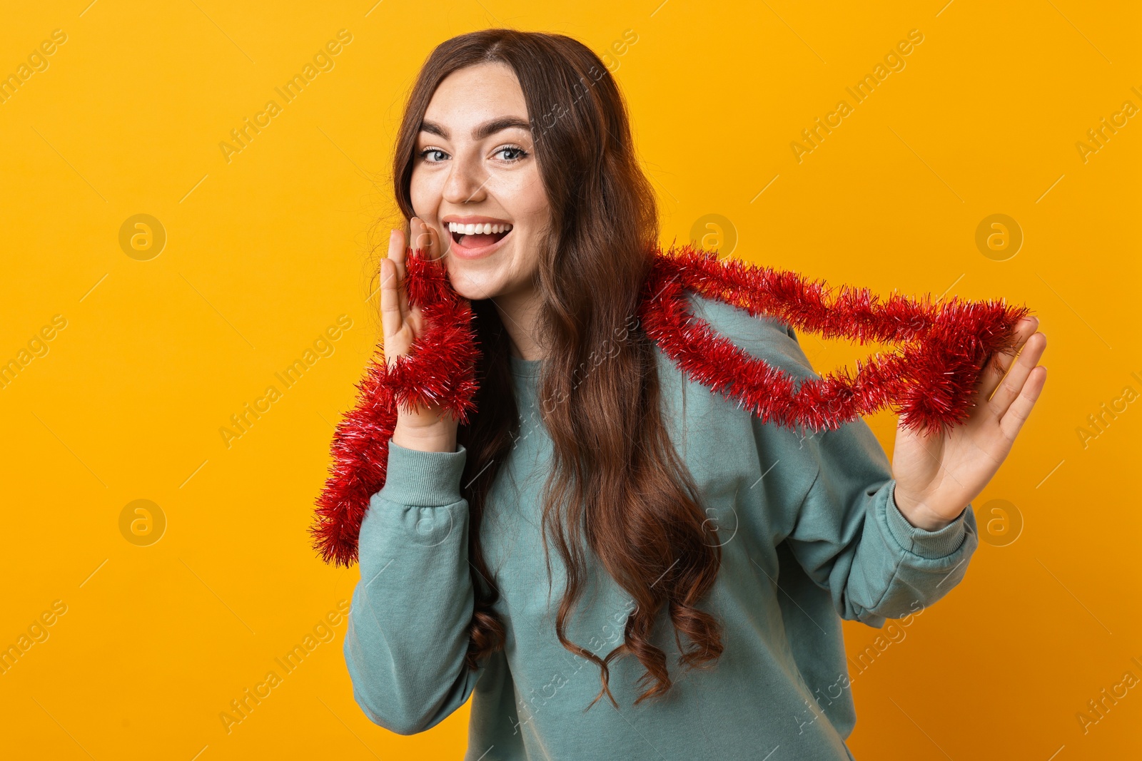 Photo of Happy young woman with tinsel on orange background